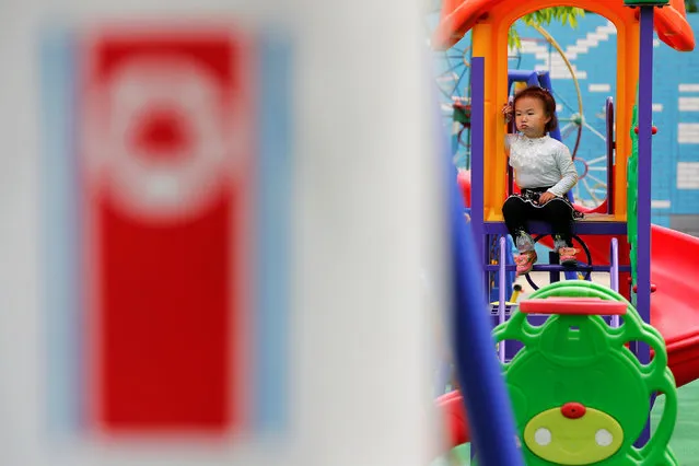 A girl sits behind a rocket shaped merry-go-around with North Korean flag at the kindergarten of the Kim Jong Suk Pyongyang textile mill during a government organised visit for foreign reporters in Pyongyang, North Korea May 9, 2016. (Photo by Damir Sagolj/Reuters)