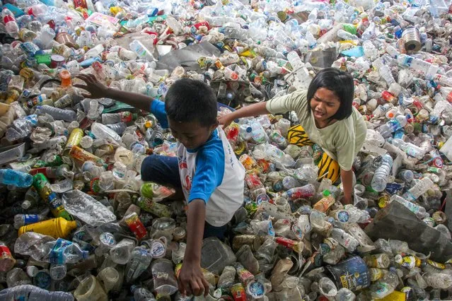 Children play in piles of plastic wastes collected for recycling in Makassar on February 11, 2022. (Photo by Andri Saputra/AFP Photo)