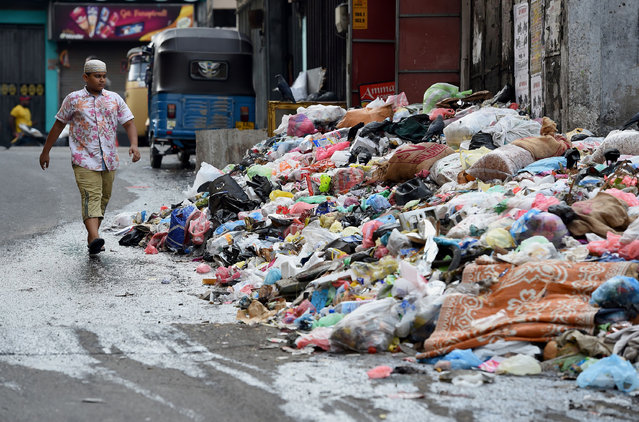 A Sri Lankan child walks by piles of garbage on a street in Colombo on April 18, 2017. Hundreds of tonnes of rotting garbage piled up in Sri Lanka's capital on April 18 after the main rubbish dump was shut following an accident that killed at least 30 people. (Photo by Ishara S. Kodikara/AFP Photo)