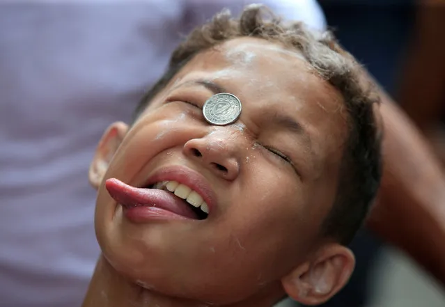 A boy reacts as he attempts to move a coin into his mouth during a game held at a town fiesta in celebration of the patron saint Santa Rita de Cascia in Baclaran, Paranaque city, metro Manila, Philippines May 22, 2016. (Photo by Romeo Ranoco/Reuters)