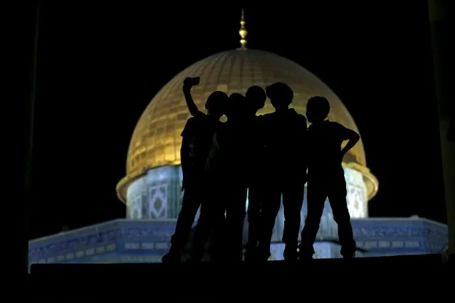 Palestinian Ali Souwan, 12, from the West Bank city of Hebron, takes a selfie photo with his friends in front of the Dome of the Rock on the compound known to Muslims as Noble Sanctuary and to Jews as Temple Mount, in Jerusalem's Old City, during the holy month of Ramadan, July 4, 2015. (Photo by Ammar Awad/Reuters)