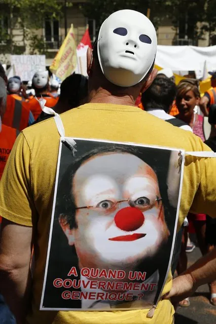 A demonstrating French tobacconist wears a placard with an image of France's President Hollande that reads, “When we will have a generic government” as he attends a protest march in Paris, France, July 22, 2015. France's tobacconists are protesting plans to force cigarette companies to use plain, unbranded packaging, as part of anti-smoking legislation. (Photo by John Schults/Reuters)