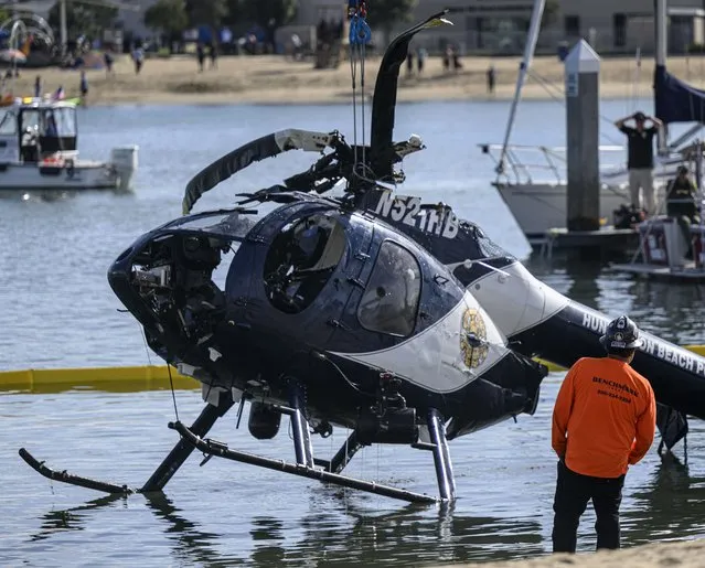 A crane is used to lift a Huntington Beach Police helicopter out of the water in Newport Beach, Calif., Sunday, February 20, 2022. Authorities were investigating the cause of a police helicopter crash along the Southern California coast that killed Huntington Beach Officer Nicholas Vella, a 14-year veteran of the force, and sent another officer to the hospital with critical injuries. (Photo by Mindy Schauer/The Orange County Register via AP Photo)