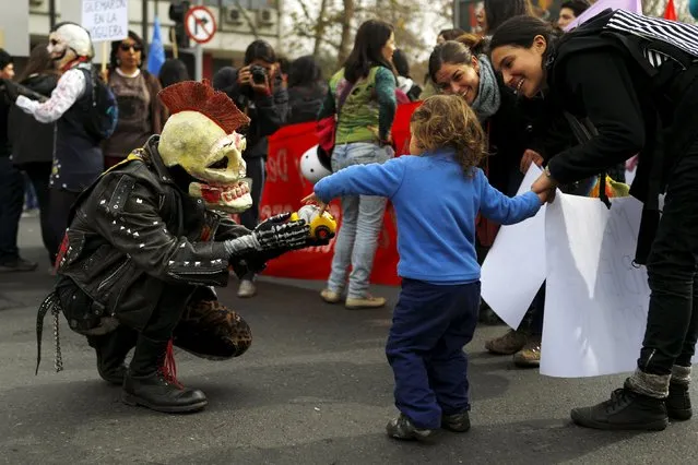 A demonstrator wearing a skull mask gives a toy car to a child during a rally held to support women's rights to an abortion in Santiago, Chile, July 25, 2015. (Photo by Ivan Alvarado/Reuters)