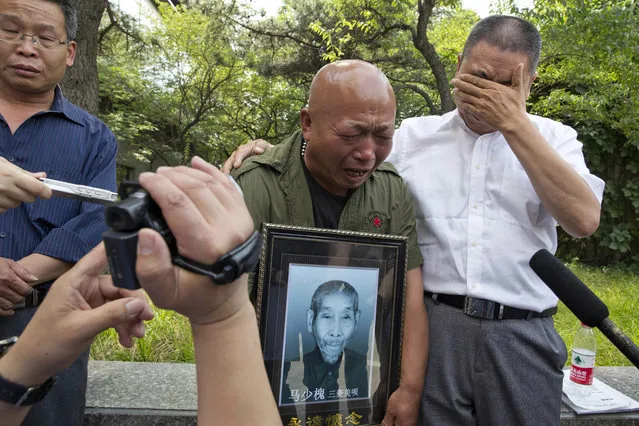 Ma Wenyi, center holds a photo of his father who was forced to work during World War II at a mine for Mitsubishi Mining Corp., cries as he talks to journalists outside a hotel where a press conference was held in Beijing, China, Wednesday, June 1, 2016. Mitsubishi Materials Corp., one of dozens of Japanese companies that used Chinese forced laborers during World War II, reached a settlement with thousands of victims on Wednesday that includes compensation and an apology. (Photo by Ng Han Guan/AP Photo)