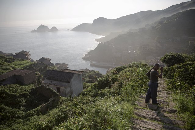 A former resident who is engaged by the local government to assist visiting tourists arrives in the abandoned fishing village of Houtouwan on the island of Shengshan as mist rises early July 26, 2015. (Photo by Damir Sagolj/Reuters)
