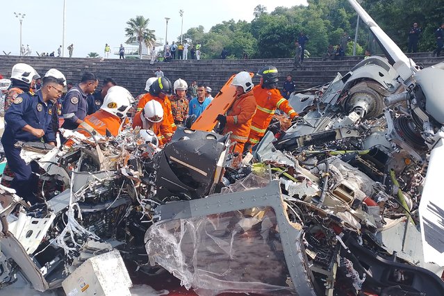 This handout picture taken and released on April 23, 2024 by Perak's Fire and Rescue Department shows rescuers inspecting the crash site after two military helicopters collided in Lumut in Malaysia's Perak state. Two Malaysian military helicopters collided and crashed during a training session on April 23, killing all 10 crew onboard, the country's rescue agency said. (Photo by Perak's Fire and Rescue Department/Handout via AFP Photo)