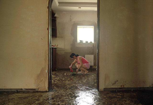 A local resident cleans mud off the floor in an apartment flooded by rising water following the collapse of the Kakhovka hydroelectric power plant dam, in Kherson on June 21, 2023. (Photo by Arthur Khanov/AFP Photo)