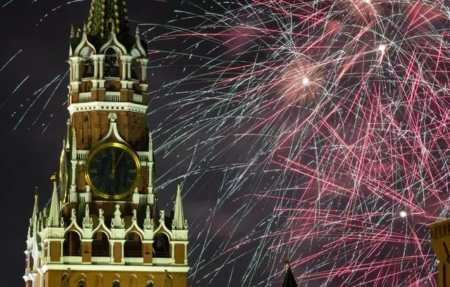 Fireworks explode over the Kremlin during New Year's celebrations in Red Square with the Spasskaya Tower in Moscow, Russia, Wednesday, January 1, 2020. Russians began the world's longest continuous New Year's Eve with fireworks and a message from President Vladimir Putin urging them to work together in the coming year. (Photo by Denis Tyrin/AP Photo)