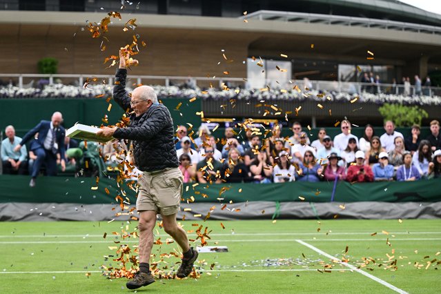 A Just Stop Oil demonstrator throws orange confetti on court 18 as he disrupts the women's singles tennis match between Australia's Daria Saville and Britain's Katie Boulter on the third day of the 2023 Wimbledon Championships at The All England Tennis Club in Wimbledon, southwest London, on July 5, 2023. (Photo by Glyn Kirk/AFP Photo)