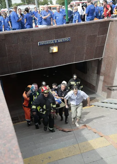 Paramedics, a police officer and a voluenteer carry an injured man out from a subway station after a rush-hour subway train derailment in Moscow, Russia, on Tuesday, July 15, 2014. A rush-hour subway train derailed in Moscow Tuesday, killing about 20 people and injuring at least 106, emergency officials said. Several cars left the track in the tunnel after a power surge triggered an alarm, which caused the train to stop abruptly. (Photo by Ivan Sekretarev/AP Photo)