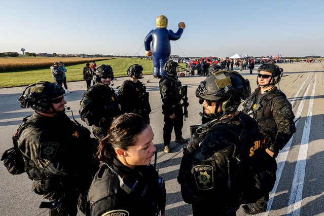 Police personnel gather near a large inflatable figure of former US President and Republican presidential nominee Donald Trump ahead of his campaign rally at the Dodge County Airport in Juneau, Wisconsin, USA, 06 October 2024. (Photo by Jeffrey Phelps/EPA/EFE)