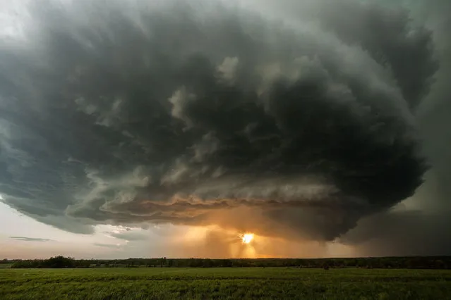 The rotating updraft base of a supercell thunderstorm, and a rear flank downdraft containing rain and hail, backlit by the setting sun, on May 10, 2014, in Climax, Kansas, United States. (Photo by Stephen Locke/Barcroft Media)
