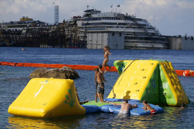 People dive in front of the cruise liner Costa Concordia at Giglio harbour, Giglio Island July 13, 2014. Italian authorities gave the green light to refloating the wrecked Costa Concordia cruise ship on Saturday, setting the stage for the next step in the largest maritime salvage in history to begin on Monday morning. (Photo by Alessandro Bianchi/Reuters)