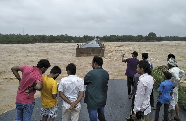 People watch after a bridge on the Deesa Dhanera highway was washed away in monsoon floods in Gujarat state, India, Tuesday, July 25, 2017. The death toll continues to rise in Gujarat since the start of the monsoon season, which runs through September. (Photo by AP Photo)