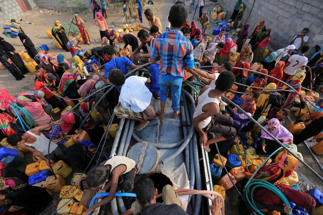 People gather around a charity tanker truck to fill up their jerrycans with drinking water in Bajil of the Red Sea province of Hodeidah, Yemen July 29, 2017. (Photo by Abduljabbar Zeyad/Reuters)