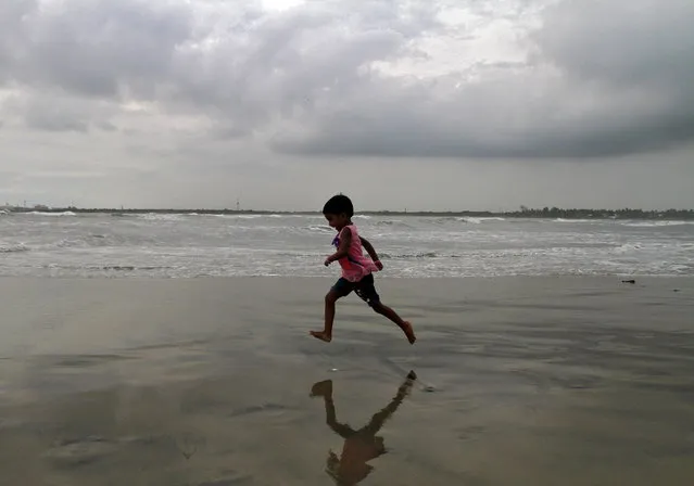 A girl runs through the beach against the backdrop of monsoon clouds at Fort Kochi beach in Kerala June 5, 2015. (Photo by Sivaram V/Reuters)