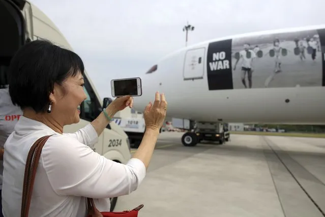 Kim Phuc, the girl in the famous 1972 Vietnam napalm attack photo, takes a picture of a plane transporting refugees fleeing the war in Ukraine to Canada, from Frederic Chopin Airport in Warsaw, Poland, Monday, July 4, 2022. Phuc's iconic Associated Press photo in which she runs with her napalm-scalded body exposed, was etched on the private NGO plane that flew the refugees Monday to the city of Regina, the capital of the Canadian province of Saskatchewan. (Photo by Michal Dyjuk/AP Photo)
