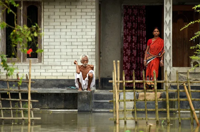A man and a woman are seen outside their partially submerged house as they wait for relief at a flooded village in Nagaon district, Assam, August 16, 2017. (Photo by Anuwar Hazarika/Reuters)