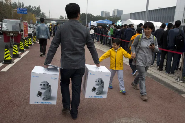 A man walks with boxes of companion robots outside the venue for the World Robot Conference in Beijing, China, Friday, October 21, 2016. (Photo by Ng Han Guan/AP Photo)