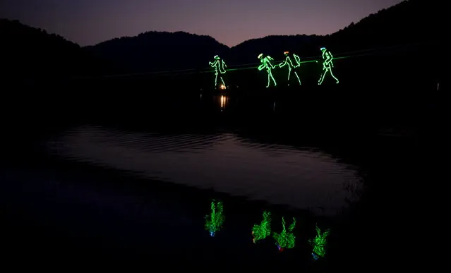 Tourists wearing LED-lit costumes walk on their way for a drifting tour at an eco-park in Changsha, Hunan province, August 23, 2015. According to local media, more than 100 people joined the first night drifting tour arranged by the park along a 1.5 km-long river on Sunday. Tourists were provided with LED-lit costumes and gears. (Photo by Reuters/Stringer)