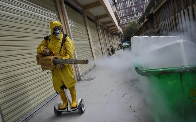 A medical staff member sprays disinfectant at a residential area in Wuhan in China's central Hubei province on March 11, 2020. China reported an increase in imported coronavirus cases on March 11, fuelling concerns that infections from overseas could undermine progress in halting the spread of the virus. (Photo by AFP Photo/China Stringer Network)