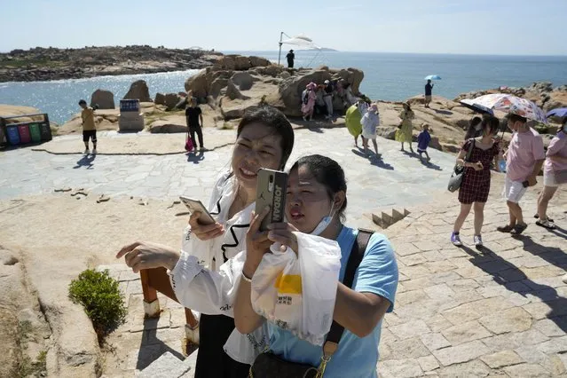 Tourists pose for photos on the waterfront at the 68-nautical-mile scenic spot, the closest point in mainland China to the island of Taiwan, in Pingtan in southeastern China's Fujian Province, Friday, August 5, 2022. (Photo by Ng Han Guan/AP Photo)