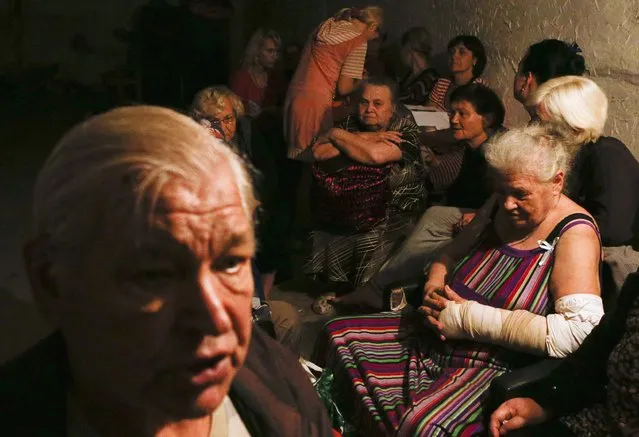 Local residents sit in a basement used as a shelter from artillery fire, in the settlement of Makiivka, on the outskirts of Donetsk, August 19, 2014. Artillery fire could be heard on Tuesday in Makiivka, on the eastern outskirts of the rebel-controlled city of Donetsk, Reuters reporters at the scene said. (Photo by Maxim Shemetov/Reuters)