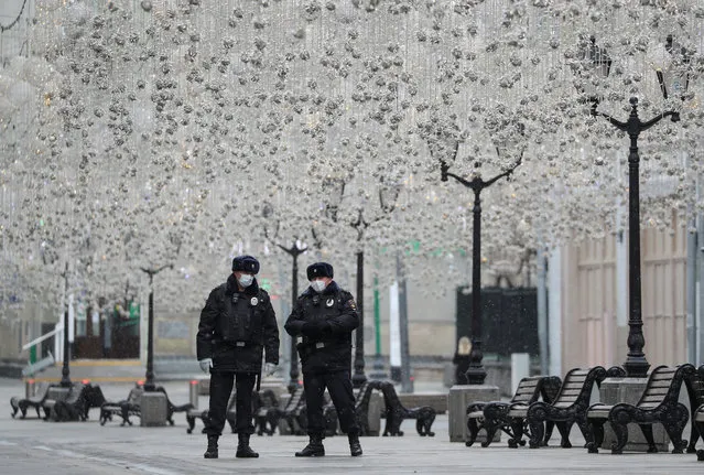 Russian law enforcement officers wearing protective masks stand guard in a street, after the city authorities announced a partial lockdown ordering residents to stay at home to prevent the spread of coronavirus disease (COVID-19), in central Moscow, Russia on March 30, 2020. (Photo by Evgenia Novozhenina/Reuters)