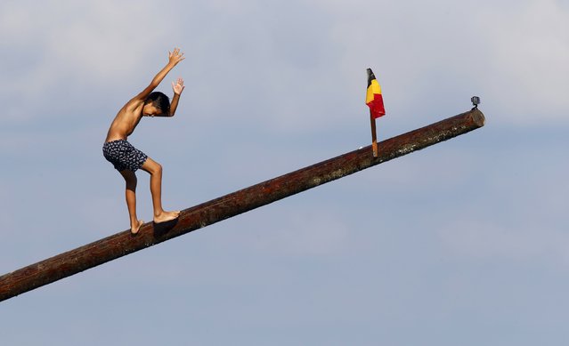 A child loses his balance on the “gostra”, a pole covered in grease, during the celebrations for the religious feast of St Julian, patron of the town of St Julian's, outside Valletta, August 30, 2015. (Photo by Darrin Zammit Lupi/Reuters)