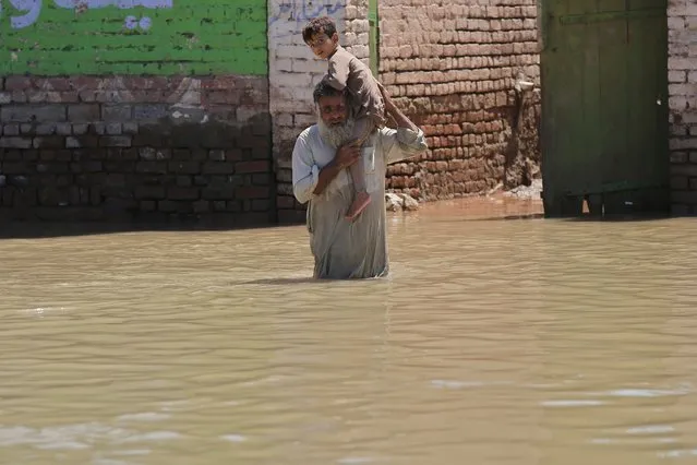 A man holding a baby wades through a flooded area following heavy rains in Charsadda District, Khyber Pakhtunkhwa province, Pakistan, 28 August 2022. According to the National Disaster Management Authority (NDMA) on 27 August, flash floods triggered by heavy monsoon rains have killed over 1,000 people across Pakistan since mid-June 2022. More than 33 million people have been affected by floods, the country's climate change minister said. (Photo by Arshad Arbab/EPA/EFE)