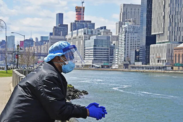 Masked New Yorker Russell Anderson, an essnetial maintenance worker at the Coler Hospital on Roosevelt Island takes an East River bank break from work on April 16, 2020. (Photo by Matthew McDermott/The New York Post)