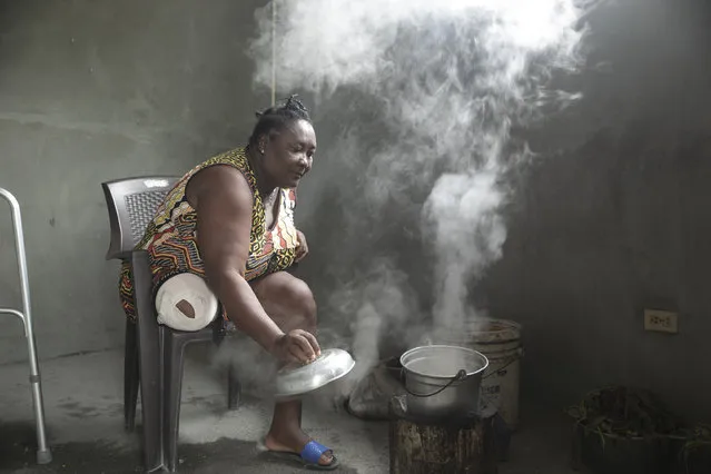 Duverseau Marie Cephta, whose leg was amputated when she was injured by last year's 7.2-magnitude earthquake, cooks in her home in the Lagodray area of Les Cayes, Haiti, Friday, August 19, 2022. (Photo by Odelyn Joseph/AP Photo)