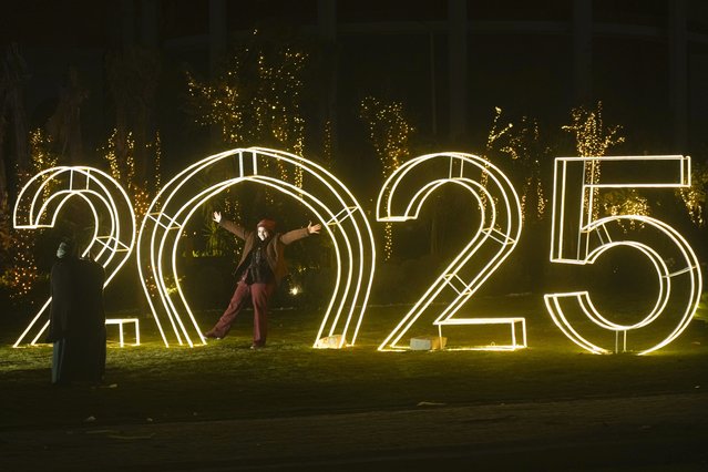 An Egyptian poses in front of New Year decorations in Cairo, Egypt, Tuesday, December 31, 2024. (Photo by Amr Nabil/AP Photo)