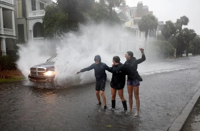 Young residents react as a truck sprays water while driving past them on a street flooded due to Hurricane Ian, in Charleston, South Carolina, U.S., September 30, 2022. (Photo by Jonathan Drake/Reuters)