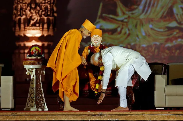 Indian Prime Minister Narendra Modi touches the feet of a saint during Akshardham temple's silver jubilee celebrations in Gandhinagar, India, November 2, 2017. (Photo by Amit Dave/Reuters)