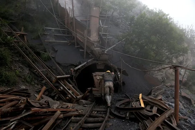 In this Thursday, May 8, 2014 photo, an Iranian coal miner pushes an old metal cart to be loaded with coal at a mine near the city of Zirab 212 kilometers (132 miles) northeast of the capital Tehran on a mountain in Mazandaran province, Iran. A miner said they move up to 100 tons a day. (Photo by Ebrahim Noroozi/AP Photo)