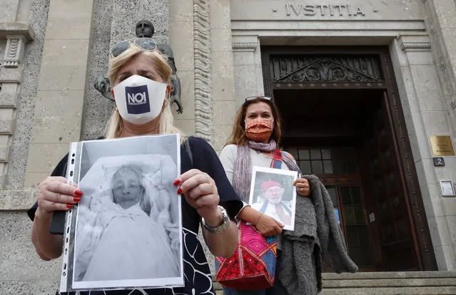 Laura Capella, left, holds up a picture of her father Mario and Nicoletta Bosica holds a photograph of her father Ernani, victims of COVID-19, as they stand in front of Bergamo's court, Italy, Wednesday, June 10, 2020. Members of an association of relatives of coronavirus victims filed a complaint with prosecutors seeking responsibility for the deaths of their loved ones. (Photo by Antonio Calanni/AP Photo)