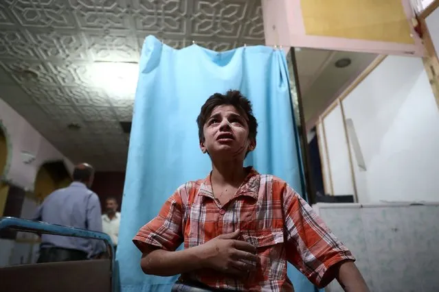 A injured boy cries as he awaits treatment at a makeshift clinic following a reported airstrike on the rebel-held town of Douma, east of the Syrian capital Damascus, on August 18, 2016. Agence France-Presse reports that more than 290,000 people have been killed and millions forced to flee their homes since Syria's conflict erupted in March 2011. (Photo by Abd Doumany/AFP Photo)