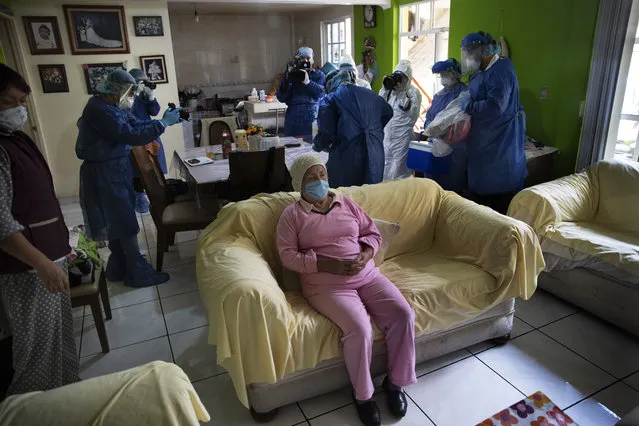 Rebeca Jimenez, 75, sits on a sofa in her home as journalists record health workers preparing to test her for COVID-19, in Mexico City, Wednesday, June 17, 2020. (Photo by Marco Ugarte/AP Photo)
