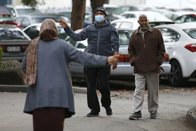 People gesture to each other as they walk outside public housing towers that are a hotspot for COVID-19 in Melbourne in Melbourne, Friday, July 10, 2020. Australia's Victoria state reported the new daily record of coronavirus cases. (Photo by Daniel Pockett/AAP Image via AP Photo)