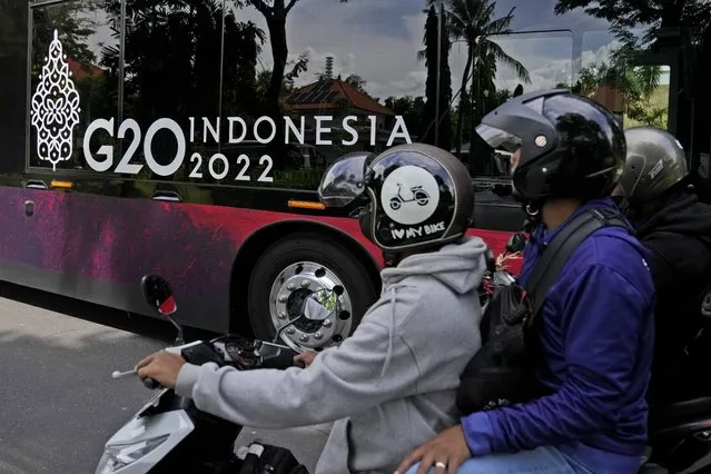 Motorists ride their bikes as a bus with a G20 sticker rolls past in Nusa Dua, Bali, Indonesia, Saturday, November 12, 2022. (Photo by Firdia Lisnawati/AP Photo)
