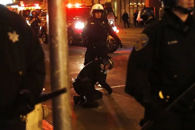 An injured police officer is seen on the ground after being hit by a glass bottle as revellers celebrate in the Mission District, in San Francisco, California October 29, 2014. (Photo by Stephen Lam/Reuters)