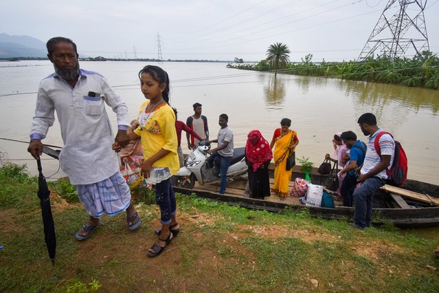 Women and children step off a wooden boat onto a grassy riverbank in Hojai district, Assam, India, on June 3, 2025. (Photo by Anuwar Hazarika/Middle East Images via AFP Photo)