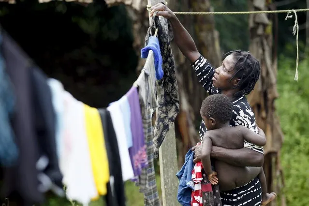 A woman carries her child as she hangs out washing outside her home in Ikarama village on the outskirts of the Bayelsa state capital, Yenagoa, in Nigeria's delta region October 8, 2015. (Photo by Akintunde Akinleye/Reuters)