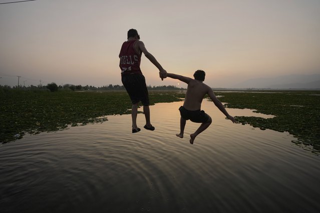 Boys jump together as they cool off on a hot summer day at Dal Lake in Srinagar, Indian-controlled Kashmir, Monday, June 23, 2025. (Photo by Mukhtar Khan/AP Photo)