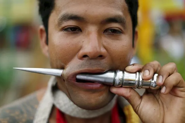 A devotee of the Chinese Samkong Shrine walks with a pierced spike through his cheek during a procession celebrating the annual vegetarian festival in Phuket, Thailand, October 16, 2015. (Photo by Jorge Silva/Reuters)