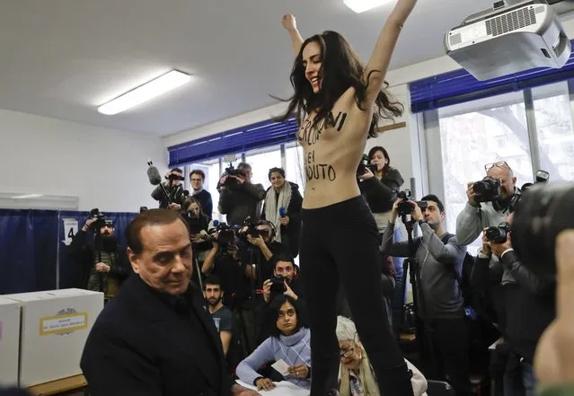 A bare-breasted woman with an Italian marker on her body reading “Berlusconi you expired” protests in front of Italian former premier and leader of Forza Italia (Go Italy) party Silvio Berlusconi at a polling station in Milan, Italy, Sunday, March 4, 2018. More than 46 million Italians were voting Sunday in a general election that is being closely watched to determine if Italy would succumb to the populist, anti-establishment and far-right sentiment that has swept through much of Europe in recent years. (Photo by Luca Bruno/AP Photo)