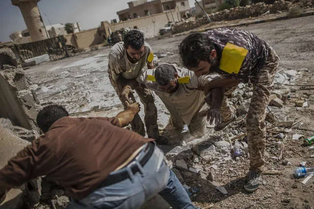 A fighter of the Libyan forces affiliated to the Tripoli government is helped by comrades after being shot by a sniper, in Sirte, Libya, Sunday, October 2, 2016. A sniper also fatally shot a Dutch photojournalist on Sunday in the Libyan city of Sirte, the Islamic State's last bastion in the chaos-wracked North African country. (Photo by Manu Brabo/AP Photo)