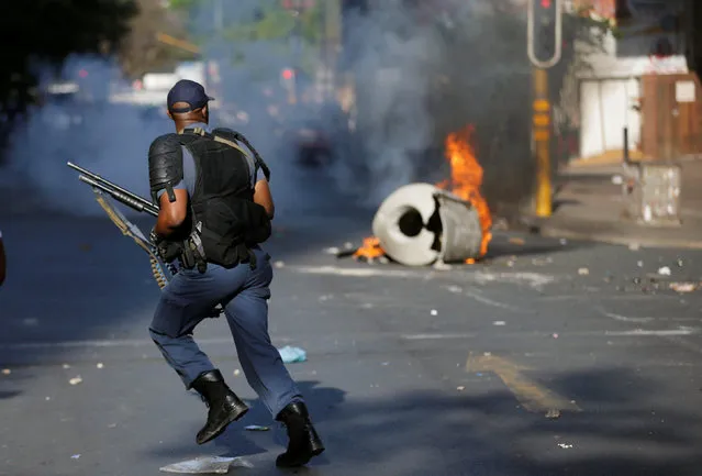 A riot police officer runs past burning barricade during clashes with students demanding free education outside the University of the Witwatersrand at Braamfontein, in Johannesburg, South Africa, October 10, 2016. (Photo by Siphiwe Sibeko/Reuters)